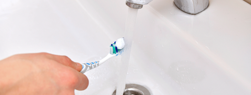 running tap water on toothbrush and toothpaste