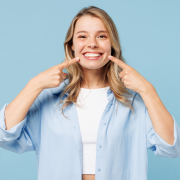 Young,Smiling,Satisfied,Happy,Woman,She,Wearing,White,Top,Shirt caucasian woman smiling and pointing to teeth